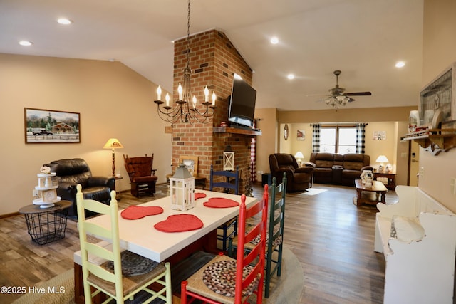 dining room with a brick fireplace, ceiling fan with notable chandelier, vaulted ceiling, and wood-type flooring