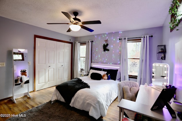 bedroom featuring multiple windows, ceiling fan, a textured ceiling, light wood-type flooring, and a closet