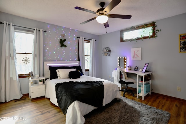 bedroom featuring multiple windows, wood-type flooring, and ceiling fan