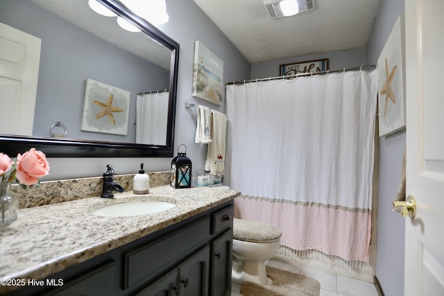 bathroom featuring vanity, toilet, tile patterned flooring, and a textured ceiling