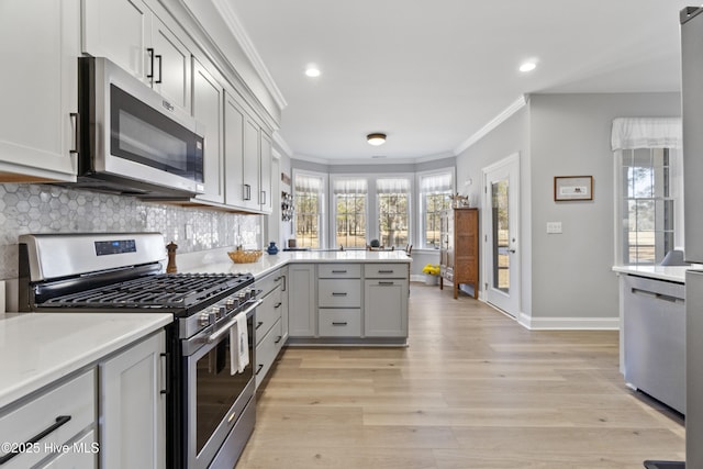 kitchen featuring stainless steel appliances, gray cabinetry, tasteful backsplash, crown molding, and light hardwood / wood-style flooring