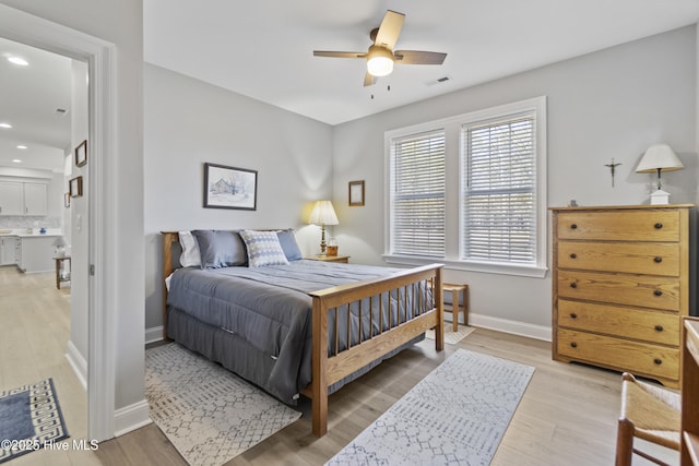 bedroom featuring ceiling fan, light hardwood / wood-style floors, and ensuite bath