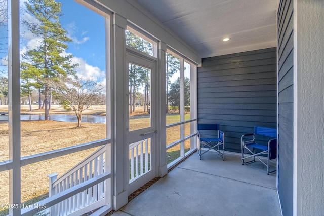 sunroom featuring a water view