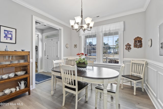 dining room featuring ornamental molding, light hardwood / wood-style flooring, and a notable chandelier