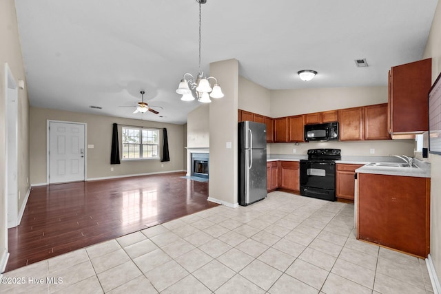 kitchen with brown cabinets, light countertops, open floor plan, a sink, and black appliances