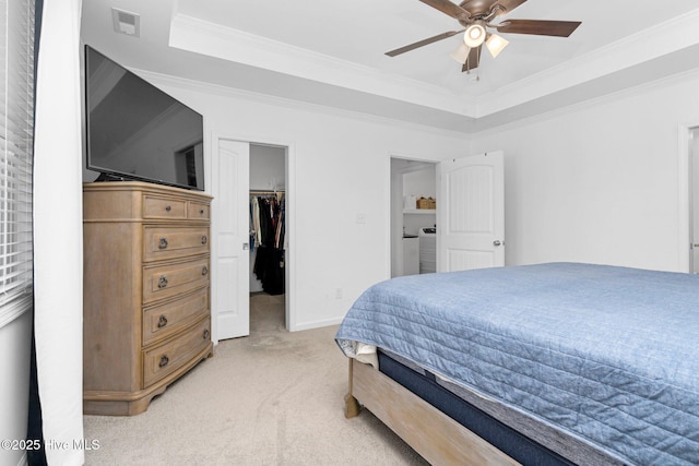 bedroom featuring a tray ceiling, a walk in closet, light carpet, and visible vents