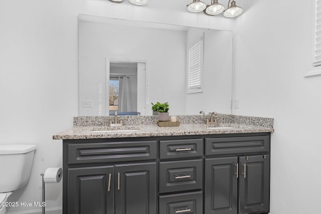 full bath featuring toilet, double vanity, and a sink