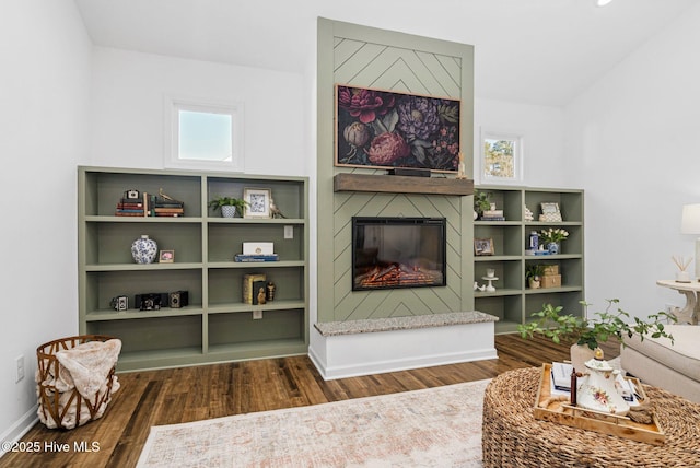 living room featuring a healthy amount of sunlight, baseboards, wood finished floors, and a glass covered fireplace