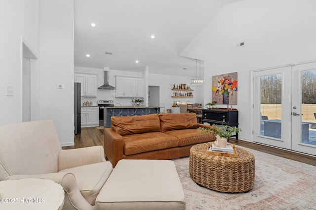 living area with recessed lighting, french doors, a high ceiling, and wood finished floors