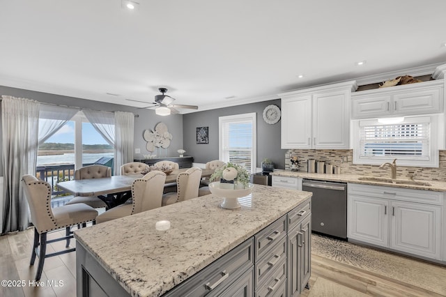 kitchen with dishwasher, a kitchen island, white cabinetry, backsplash, and a water view