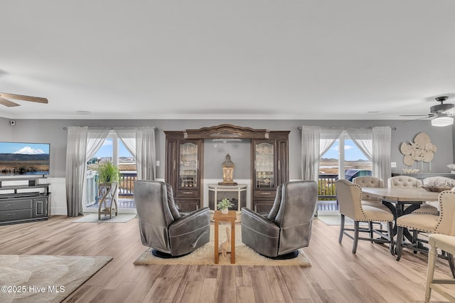 living room featuring ceiling fan, plenty of natural light, and crown molding