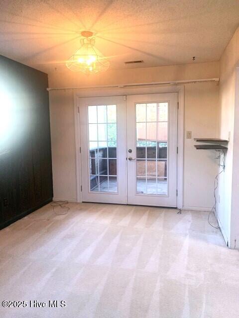 doorway featuring a textured ceiling, light colored carpet, and french doors