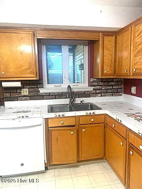 kitchen with tasteful backsplash, tile countertops, sink, and white dishwasher