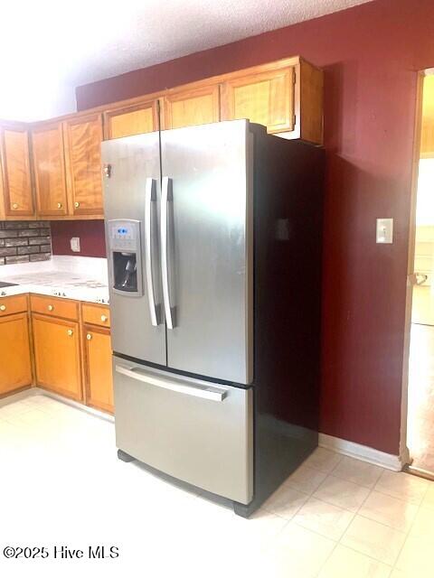 kitchen featuring a textured ceiling, stainless steel fridge with ice dispenser, and tasteful backsplash