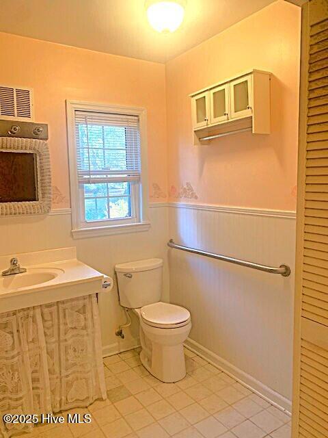 bathroom featuring sink, tile patterned floors, toilet, and wooden walls