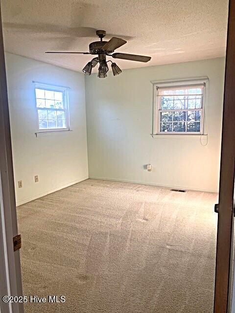 empty room with ceiling fan, a textured ceiling, and carpet