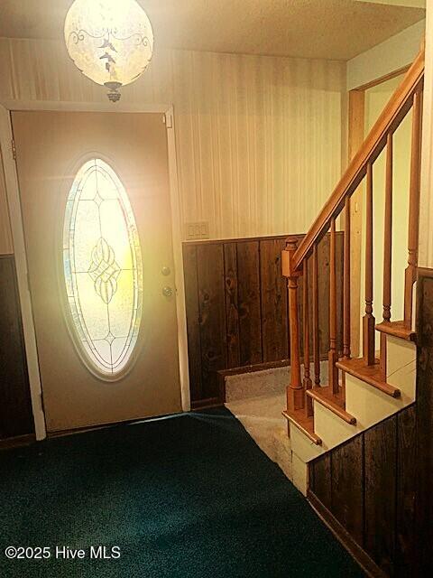 foyer with carpet and wood walls