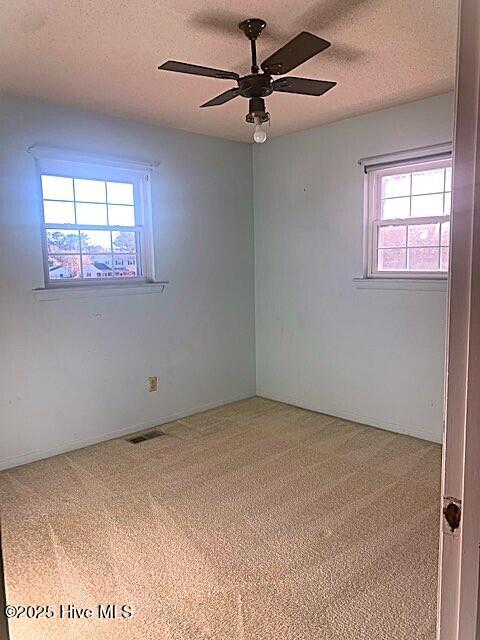 carpeted empty room featuring ceiling fan and a textured ceiling