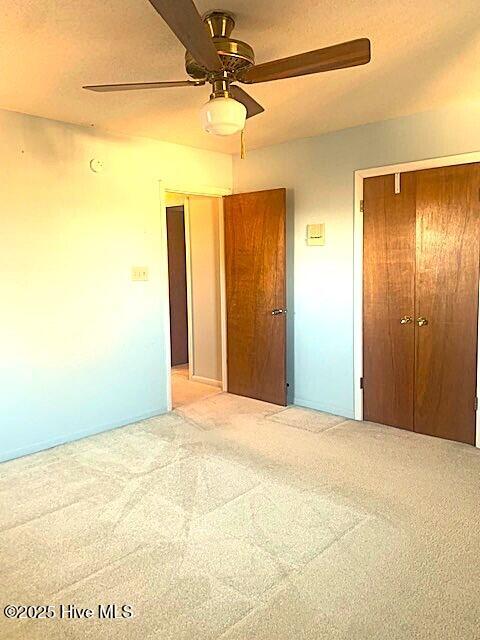 unfurnished bedroom featuring light carpet, ceiling fan, and a closet