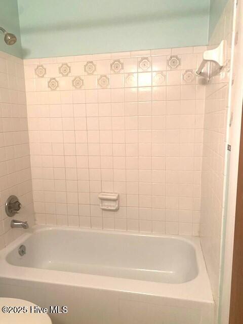 bathroom with toilet and tiled shower / bath