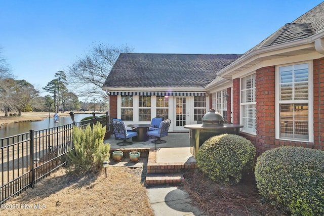 view of patio / terrace featuring a water view, a grill, and french doors