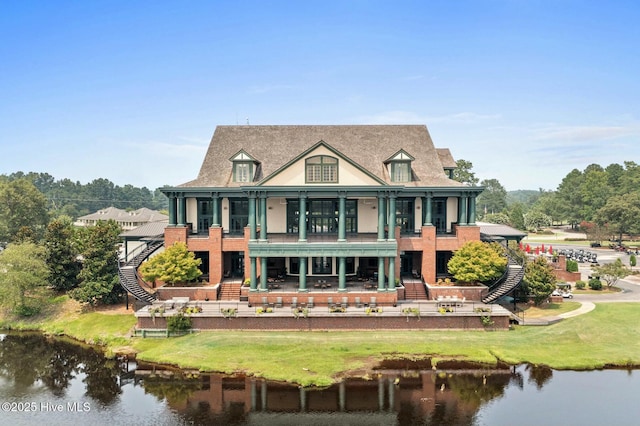 back of house featuring a lawn, a balcony, and a water view