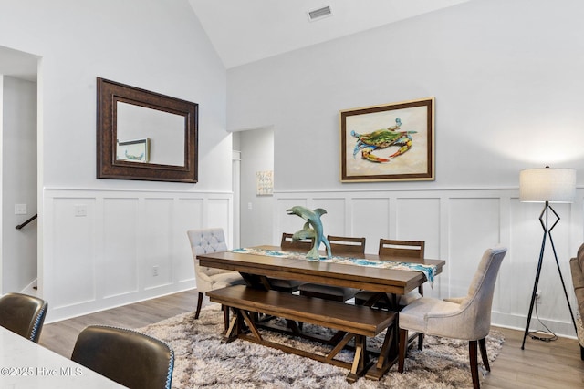 dining space featuring wood-type flooring and vaulted ceiling