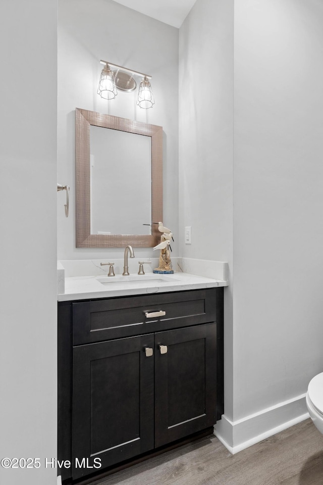 bathroom with hardwood / wood-style flooring, toilet, and vanity