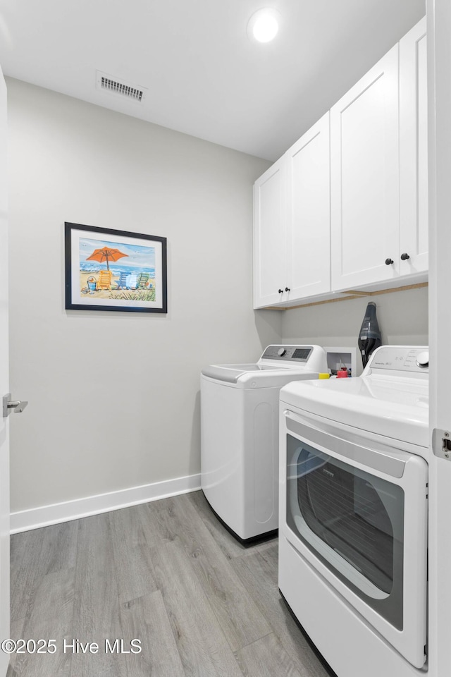 laundry room with light hardwood / wood-style floors, cabinets, and washer and dryer