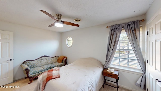 carpeted bedroom with ceiling fan and a textured ceiling