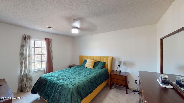 bedroom with light carpet, ceiling fan, and a textured ceiling