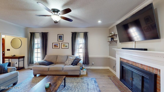living room with crown molding, a healthy amount of sunlight, hardwood / wood-style floors, and a brick fireplace