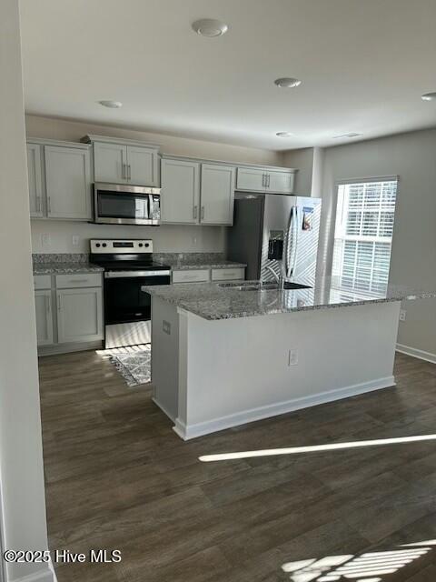 kitchen featuring a kitchen island, stainless steel appliances, white cabinets, dark hardwood / wood-style flooring, and light stone counters