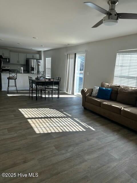 living room with dark wood-type flooring and ceiling fan