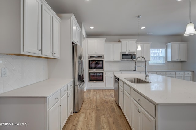 kitchen featuring white cabinetry, a center island with sink, appliances with stainless steel finishes, and a sink