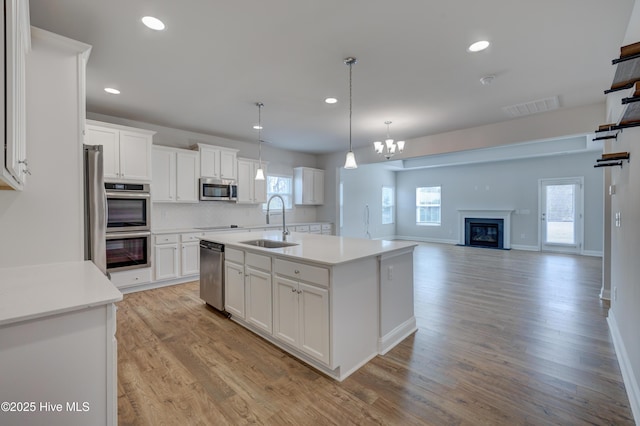 kitchen with stainless steel appliances, a sink, visible vents, and white cabinetry