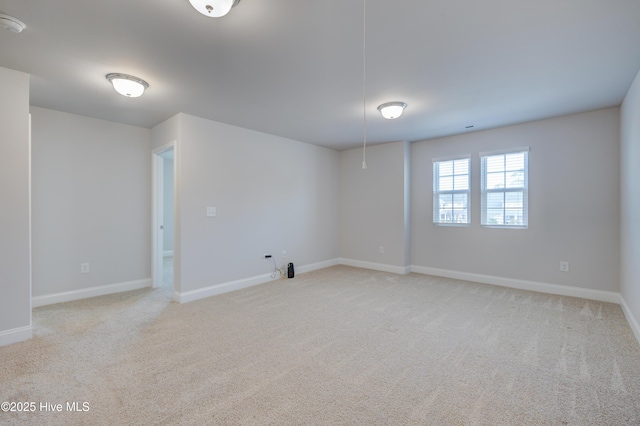 unfurnished room with baseboards and light colored carpet