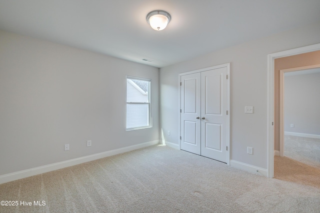 unfurnished bedroom featuring carpet floors, a closet, visible vents, and baseboards