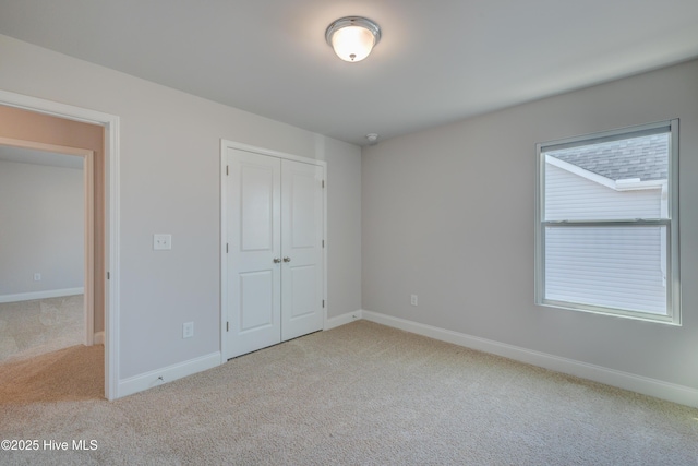 unfurnished bedroom featuring carpet, baseboards, and a closet