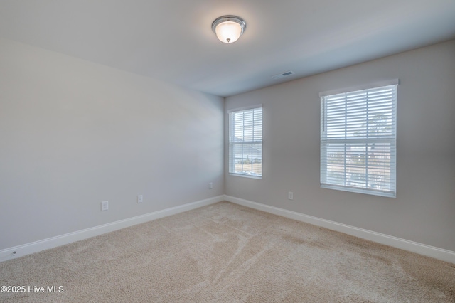 unfurnished room with visible vents, light carpet, and baseboards