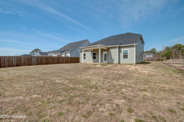 back of property with fence and a yard