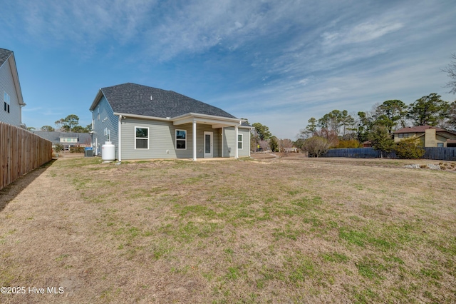 back of house with central AC, fence, and a lawn