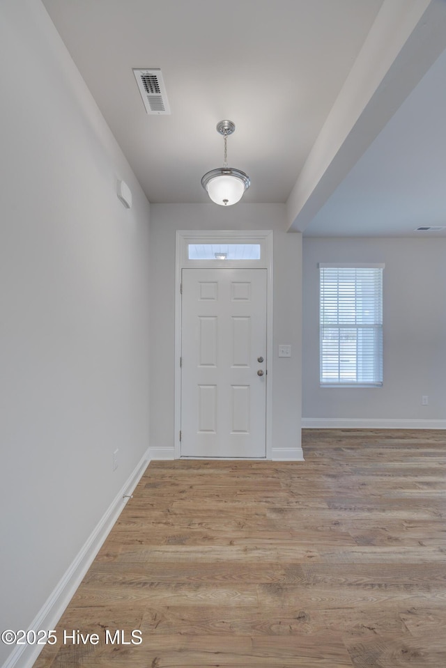 foyer entrance with visible vents, light wood-style flooring, and baseboards