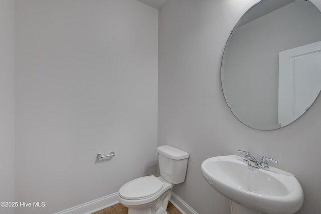 bathroom featuring wood finished floors, a sink, toilet, and baseboards