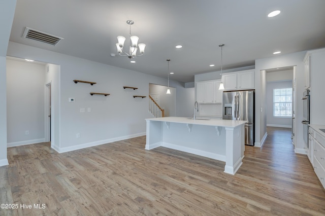 kitchen featuring stainless steel appliances, light countertops, visible vents, light wood-style floors, and a sink