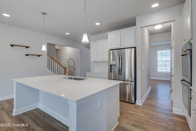 kitchen with wood finished floors, stainless steel refrigerator with ice dispenser, a sink, and white cabinets