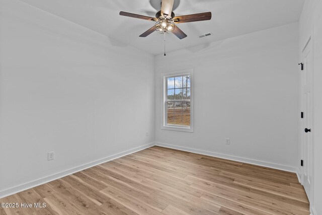 spare room featuring light wood finished floors, baseboards, visible vents, and ceiling fan