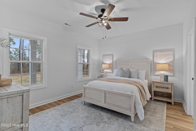 bedroom featuring ceiling fan, wood finished floors, visible vents, and baseboards