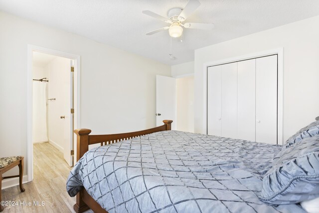 bedroom with a textured ceiling, ceiling fan, light hardwood / wood-style floors, and multiple windows