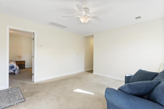 living area with ceiling fan, light colored carpet, and a wealth of natural light